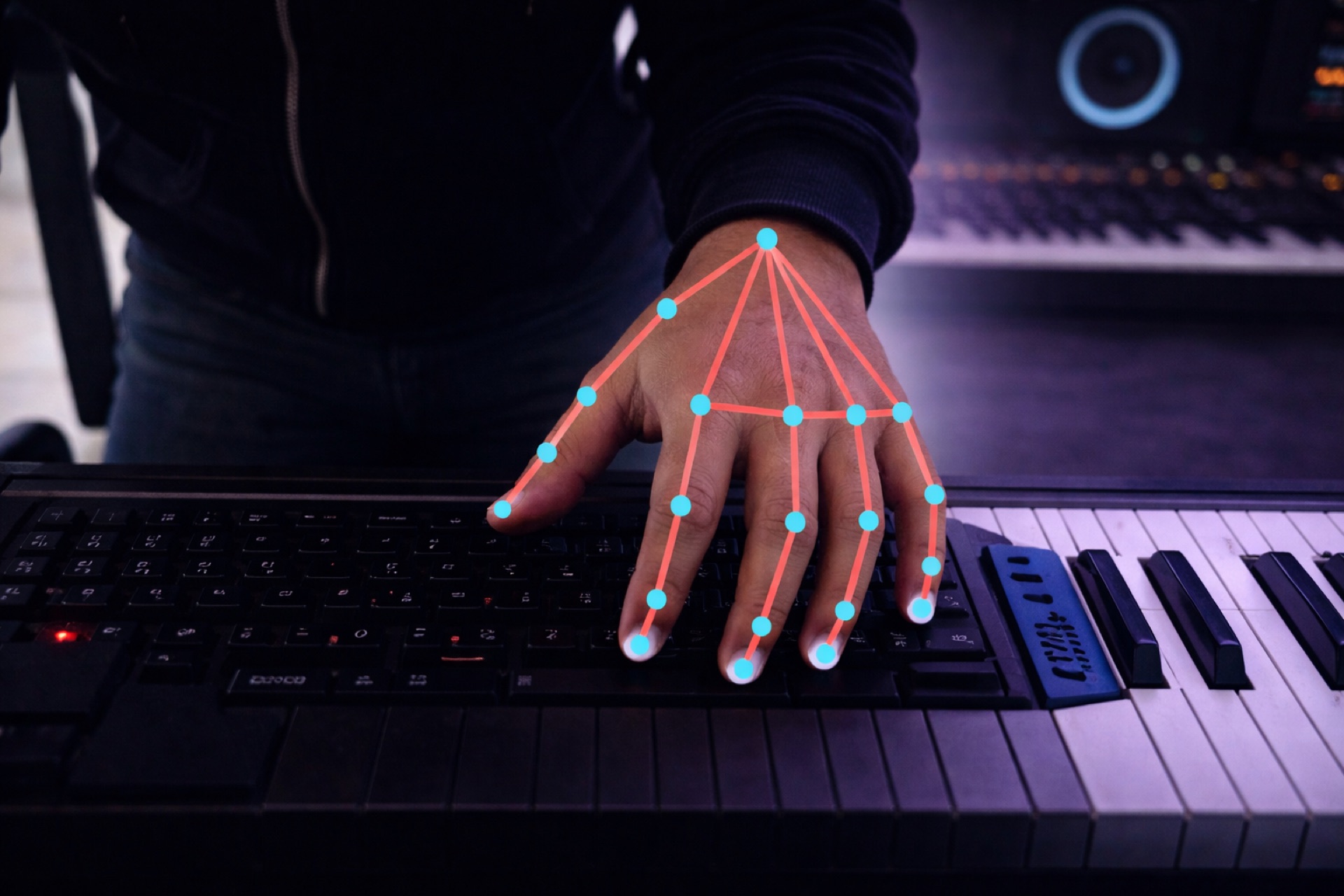 Hand with MediaPipe skeleton landmarks tracking over a MIDI keyboard in a music production studio